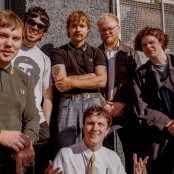 Madra Salach stood in front of a grey building